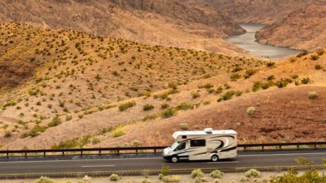RV driving down highway near the river.